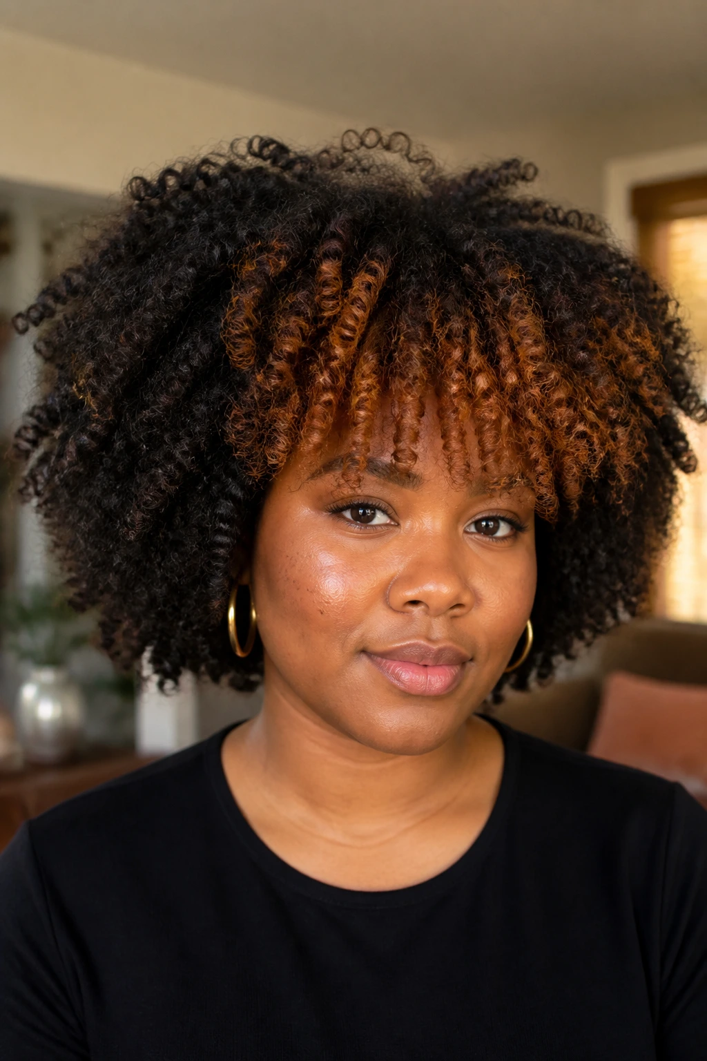 Portrait of a person with afro-textured coils and pumpkin spice fringe.