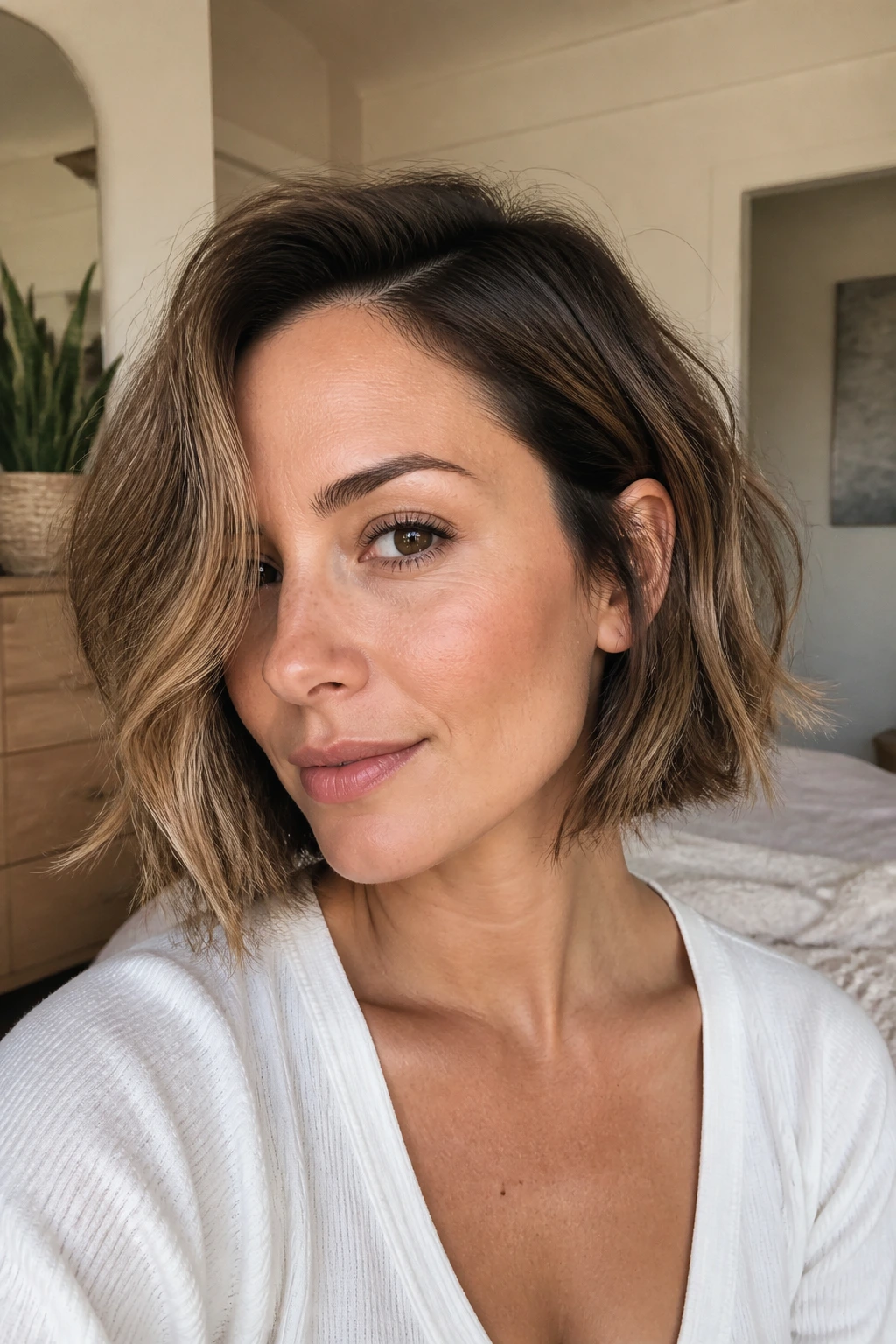 Close-up of a real woman with a textured beachy side-part bob in natural window light