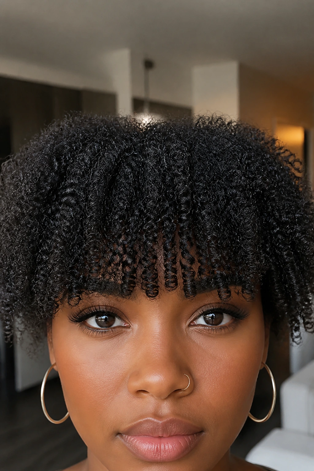 Close-up of a real person with a bold blunt coily fringe on the forehead