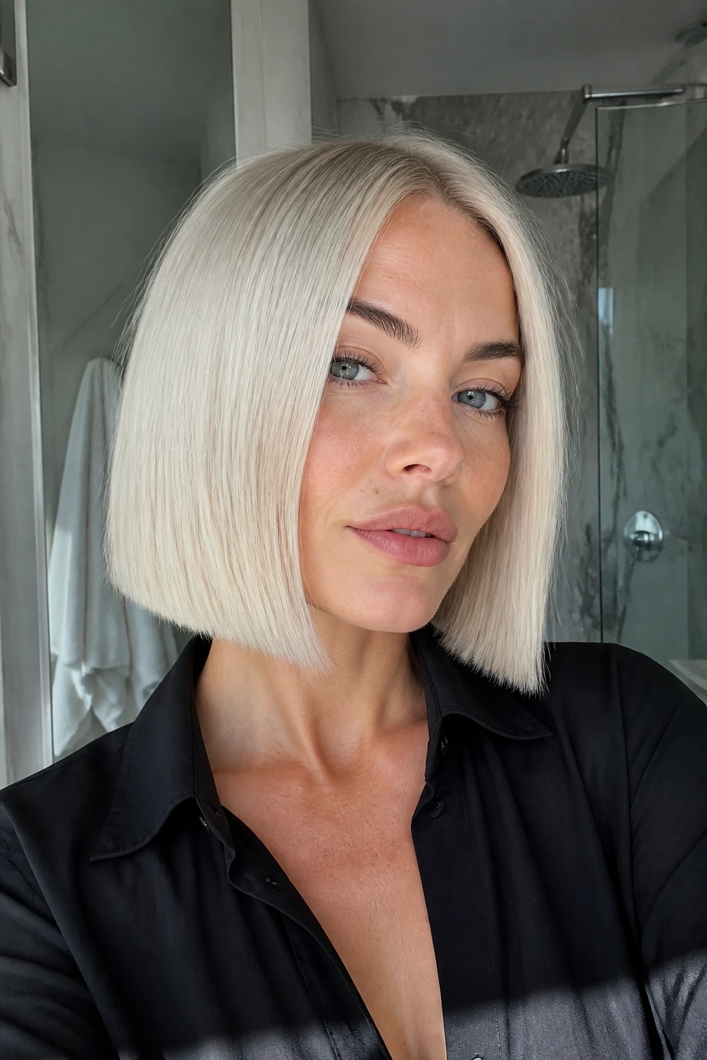 Close-up of a real woman with a blunt platinum chop under cool bathroom lighting