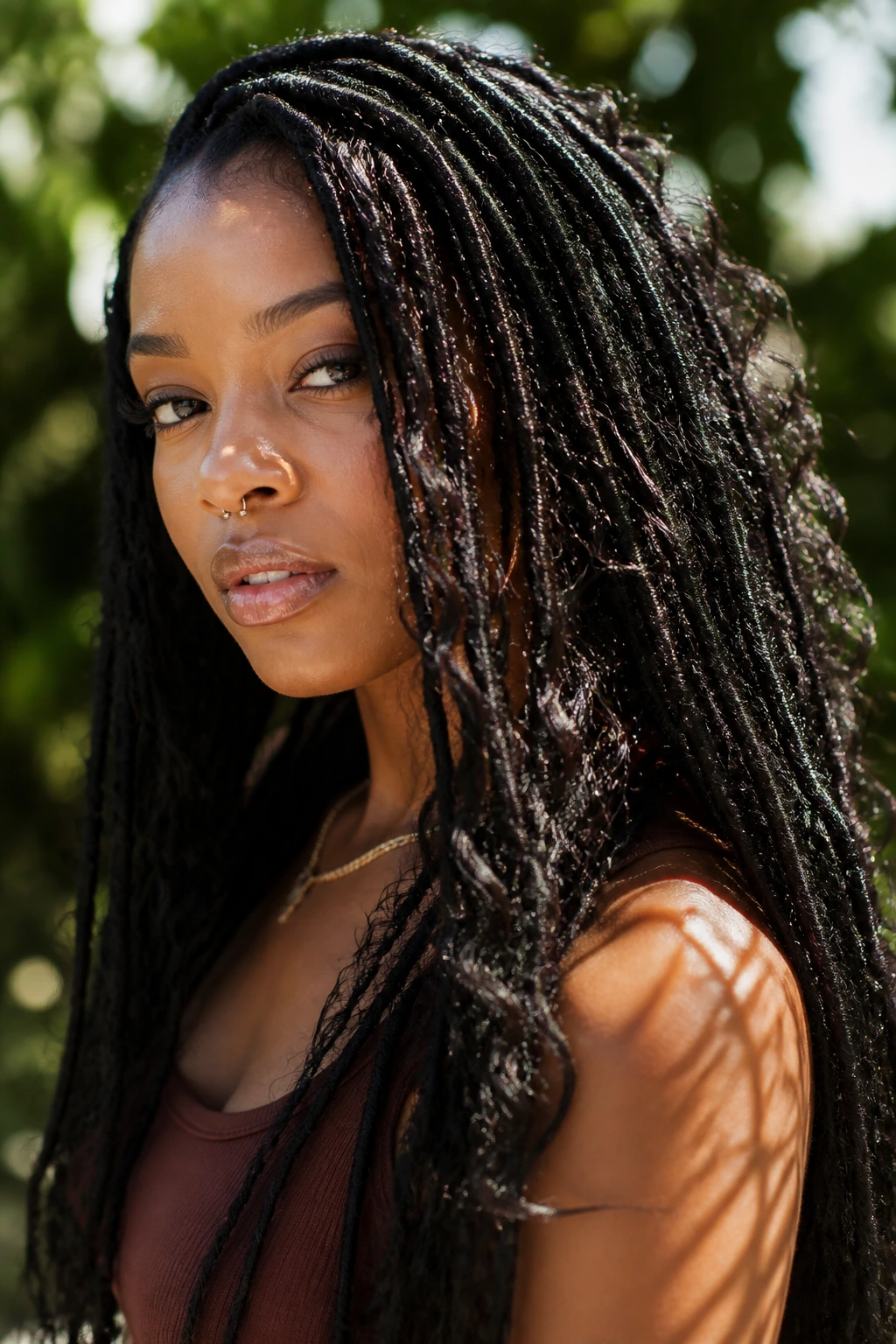 Close-up of Bohemian Locs on a real person in a sunlit garden with loose curls
