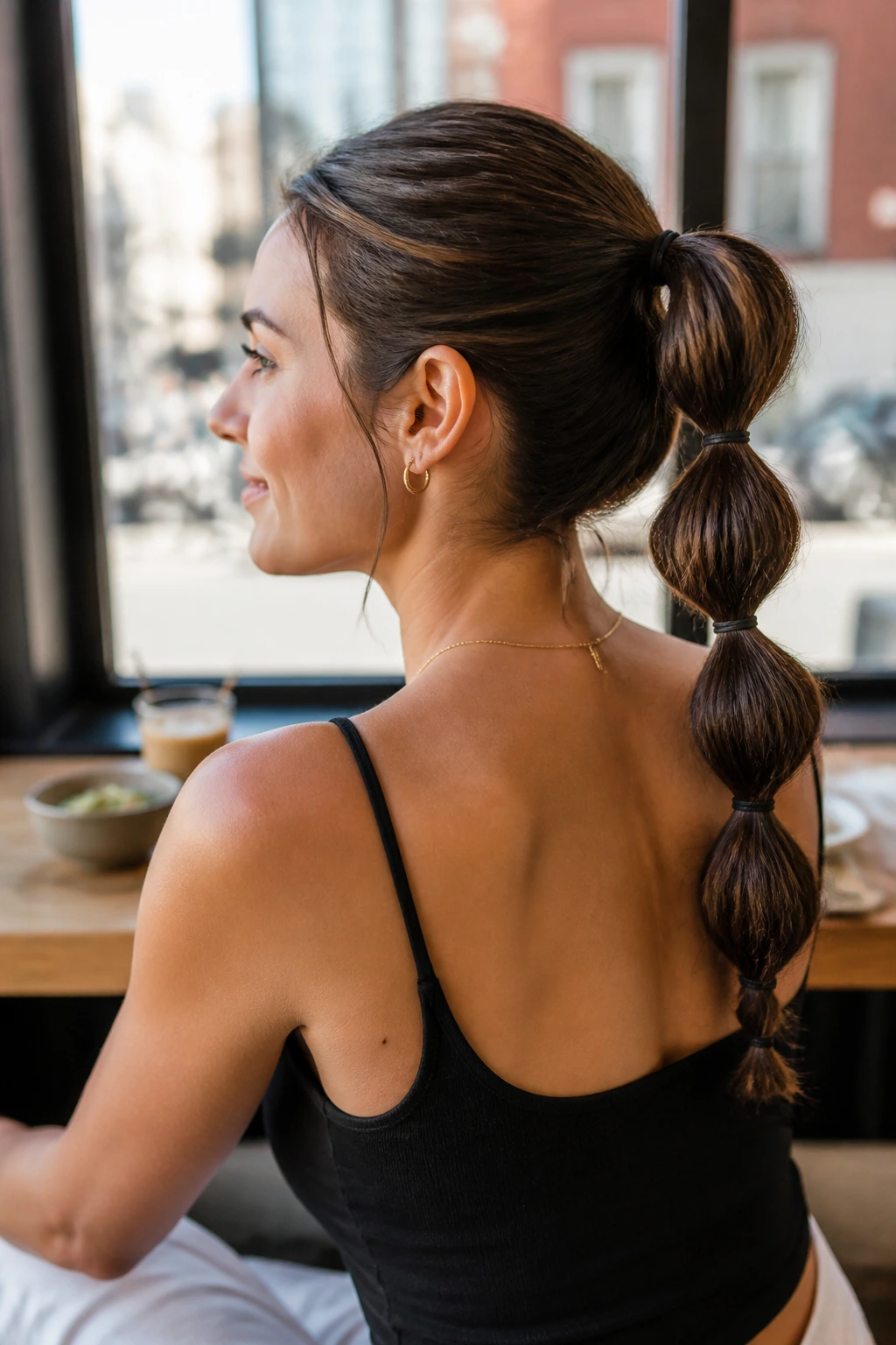 Real woman with bubble ponytail made of segmented elastics on damp hair