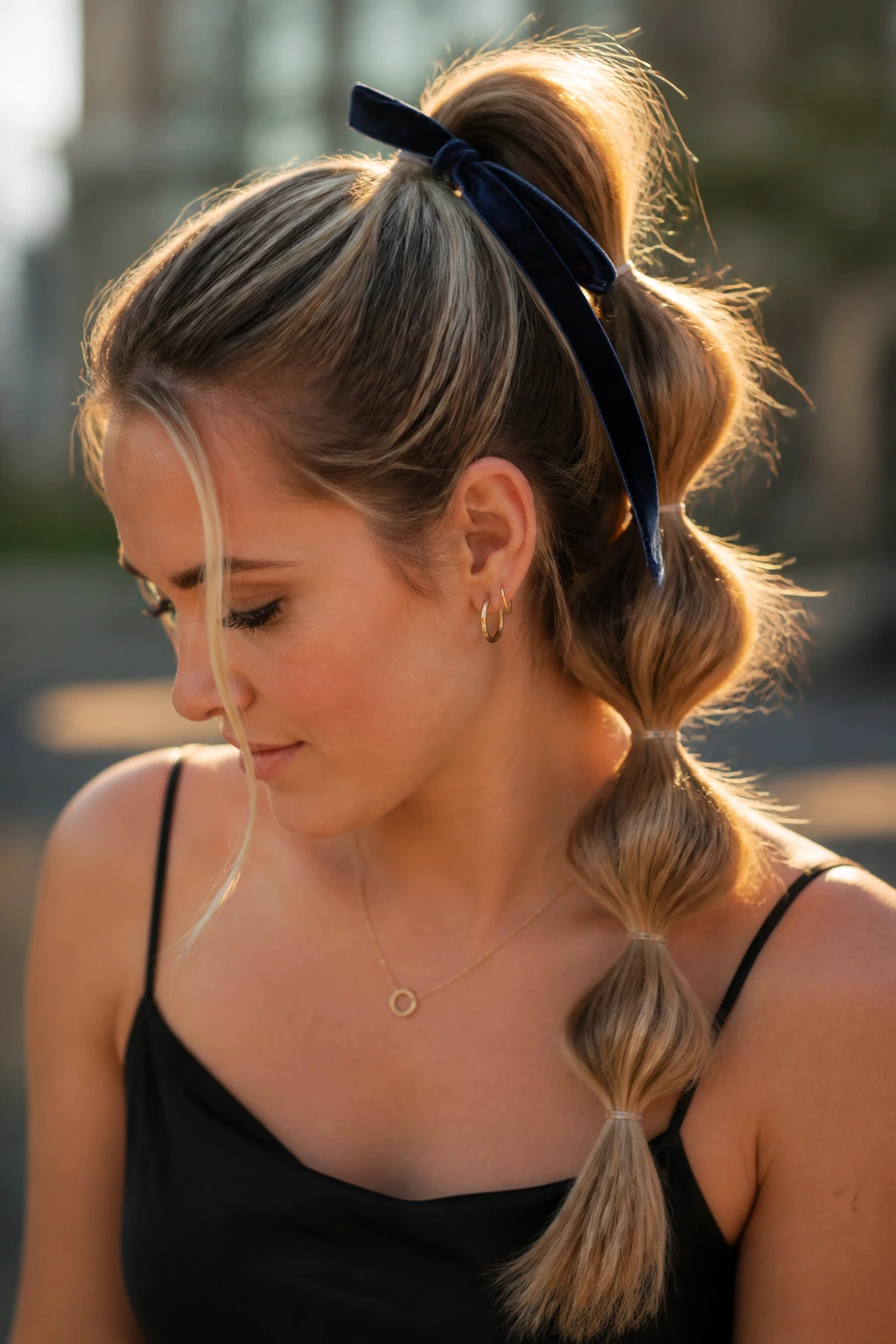 Portrait of a woman with a bubble ponytail featuring clear elastics and a velvet ribbon.