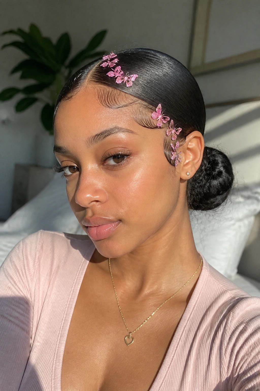 Close-up of a real woman with a sleek low bun and pink butterfly edges in natural light