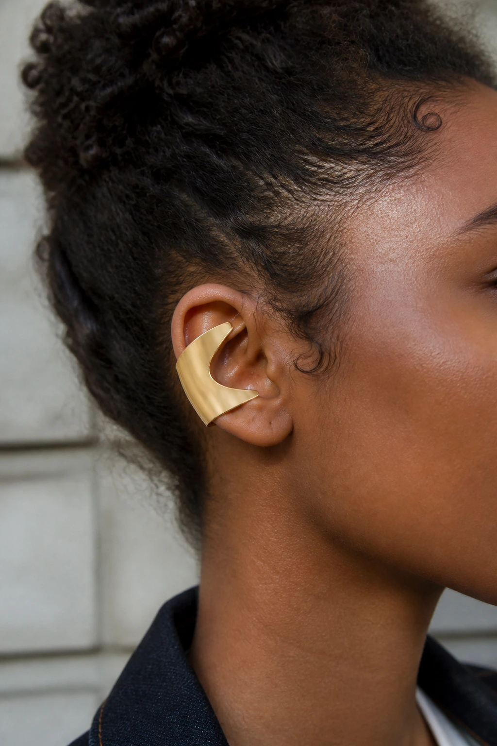 Close-up of ear with wide geometric C-shaped cuff on a real person with curly hair