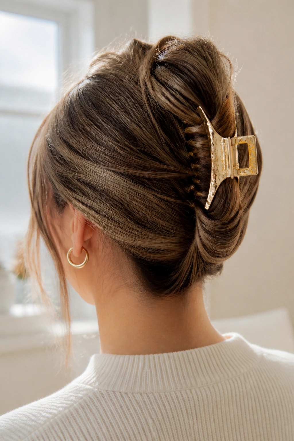 Back view of a head showing a French twist secured with a gold claw clip