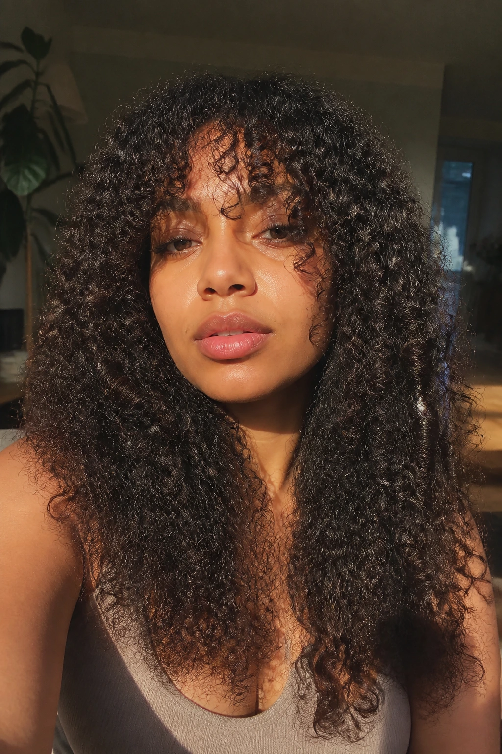 Close-up of a real person with layered coily hair and long split bangs around the eyes