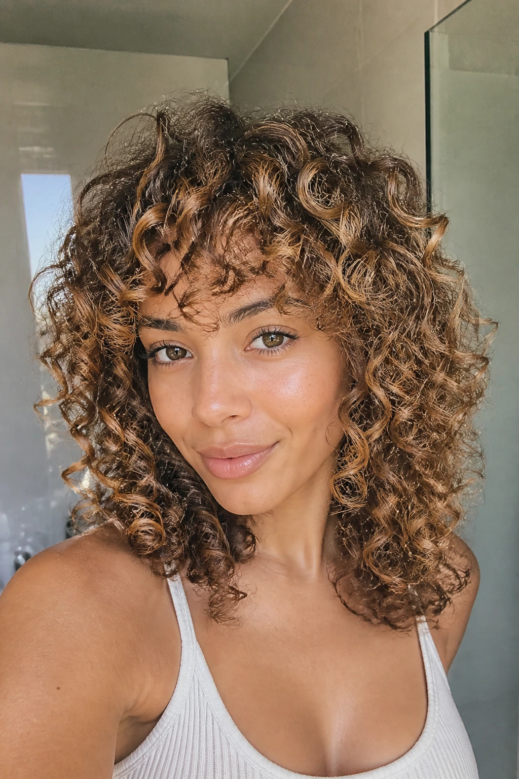 Real person with vibrant color-treated curls in bright bathroom