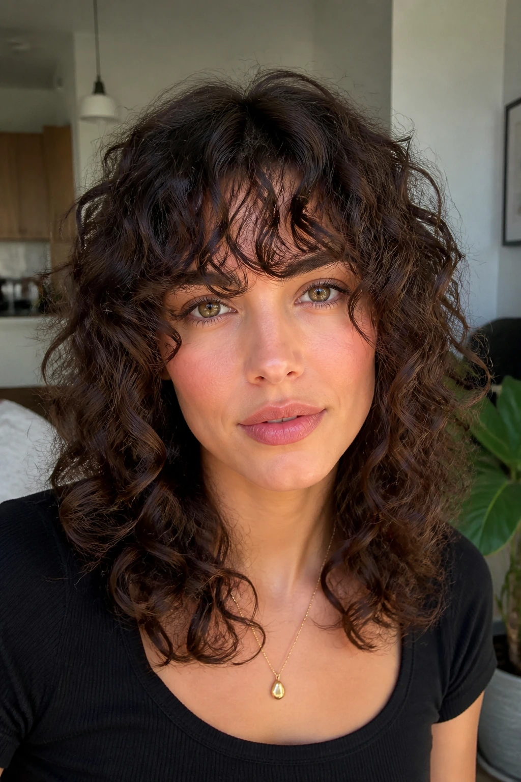 Close-up of a real woman with curly shag and hydrated bangs in bright indoor light.