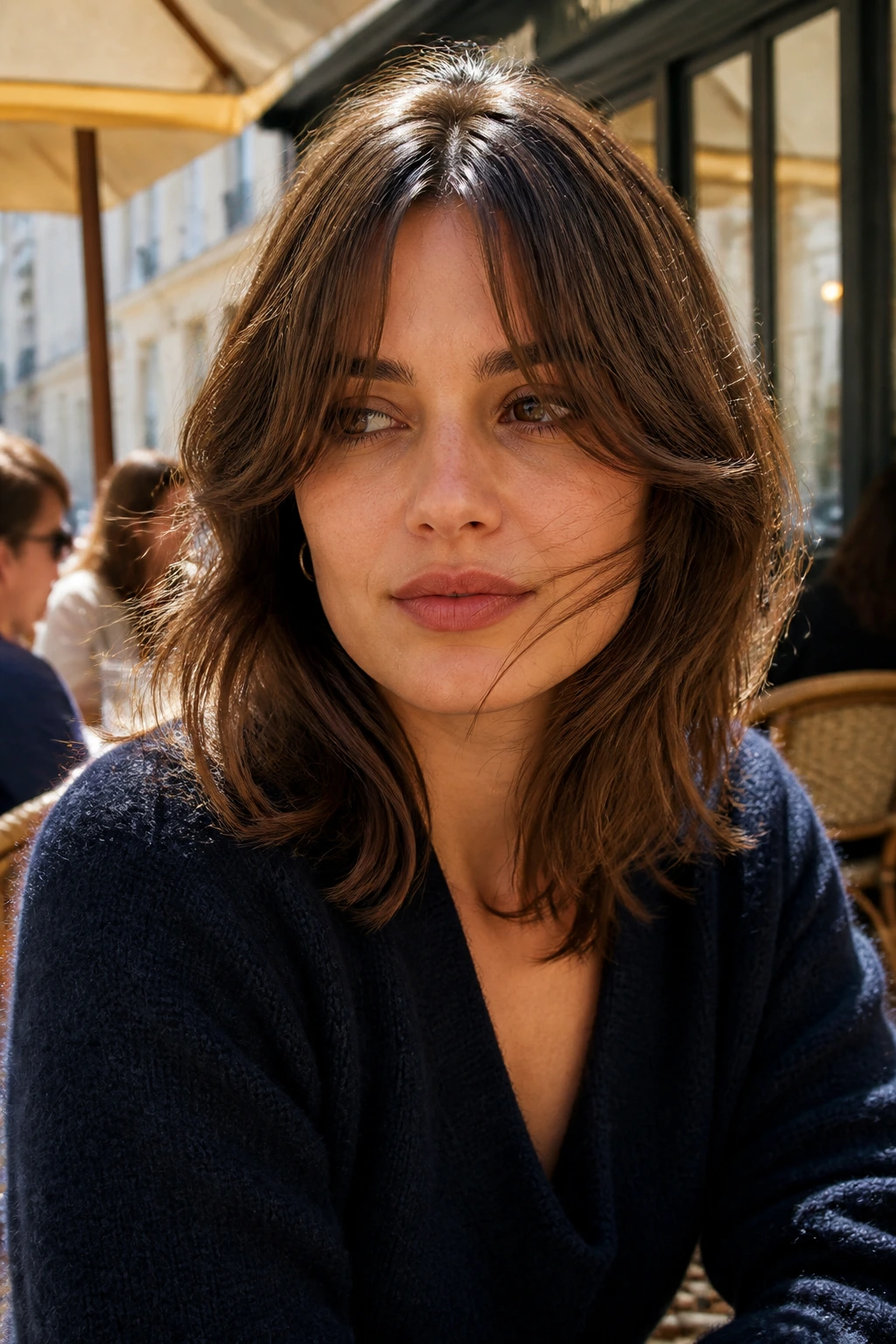 Medium close-up of a real woman with curtain bangs at an outdoor cafe
