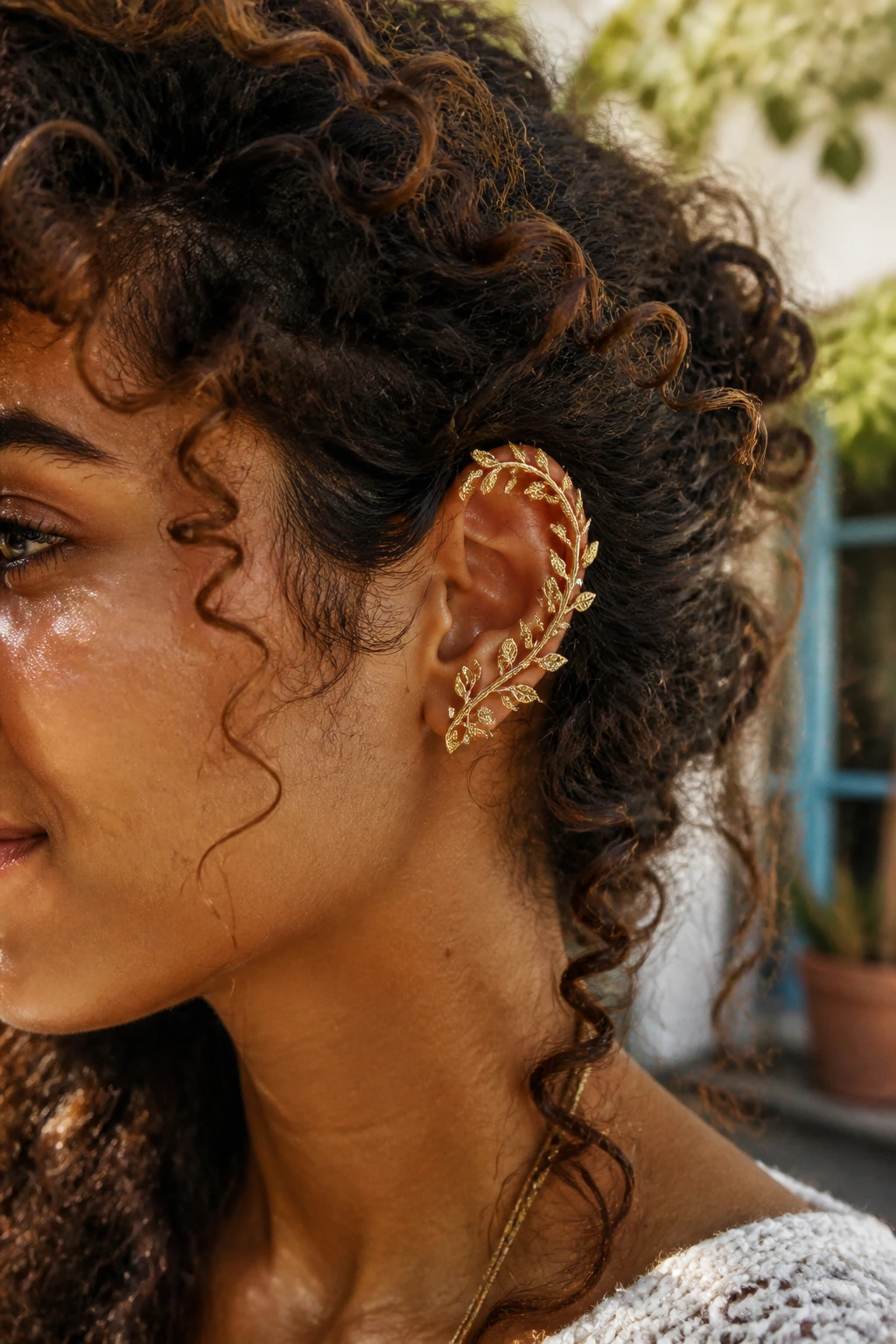 Close-up of ear with vine-like ear wrap cuff on curly hair in sunlight