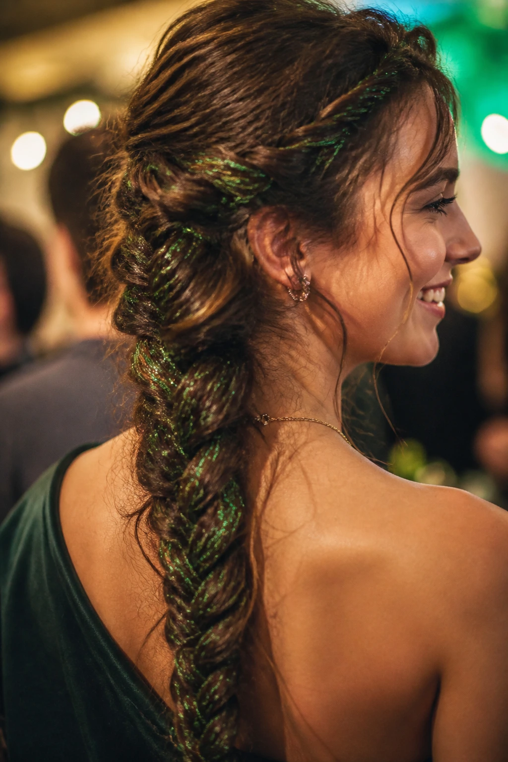 Close-up of a fishtail braid with green tinsel strands on a real person.