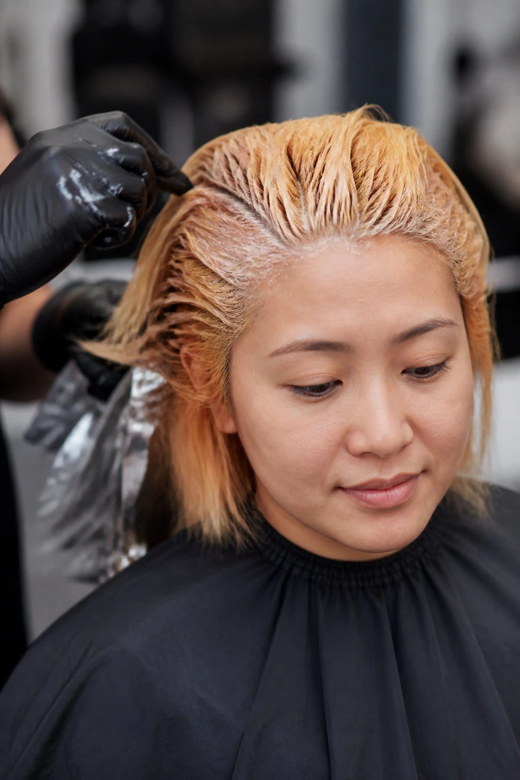 Close-up of a person in a salon during hair bleaching to orange tones.