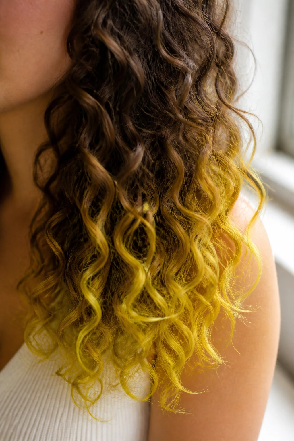 Close-up of real woman's hair tips dyed lemon-yellow chalk.