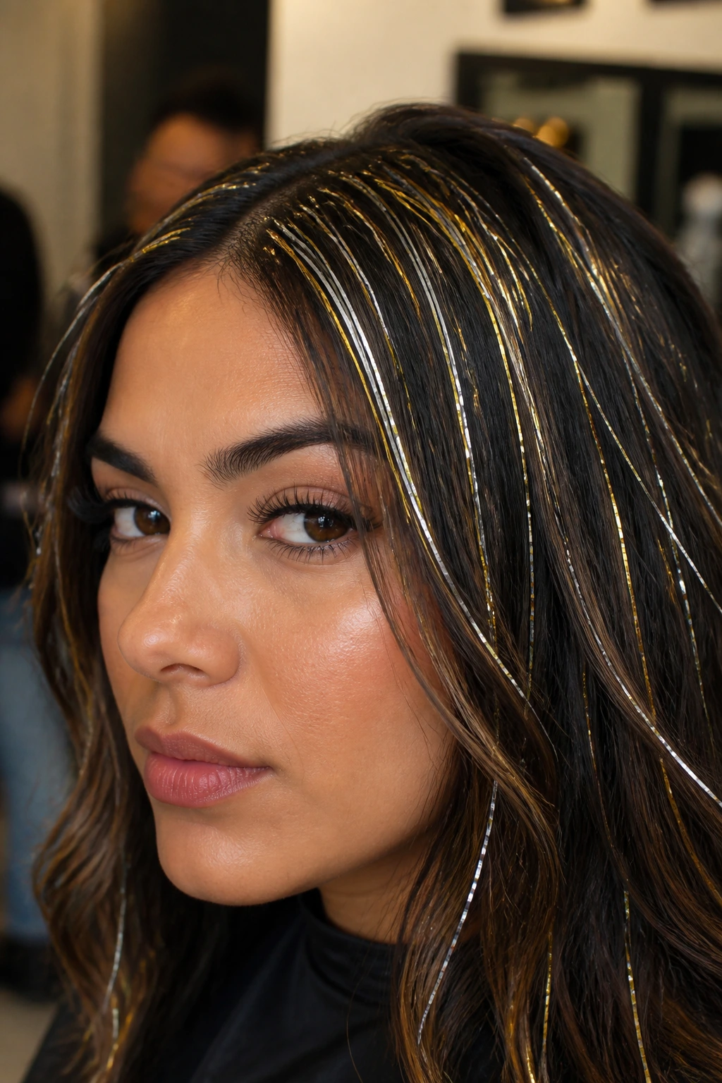 Close-up of real woman with metallic hair tinsel woven at roots, shimmering gold and silver