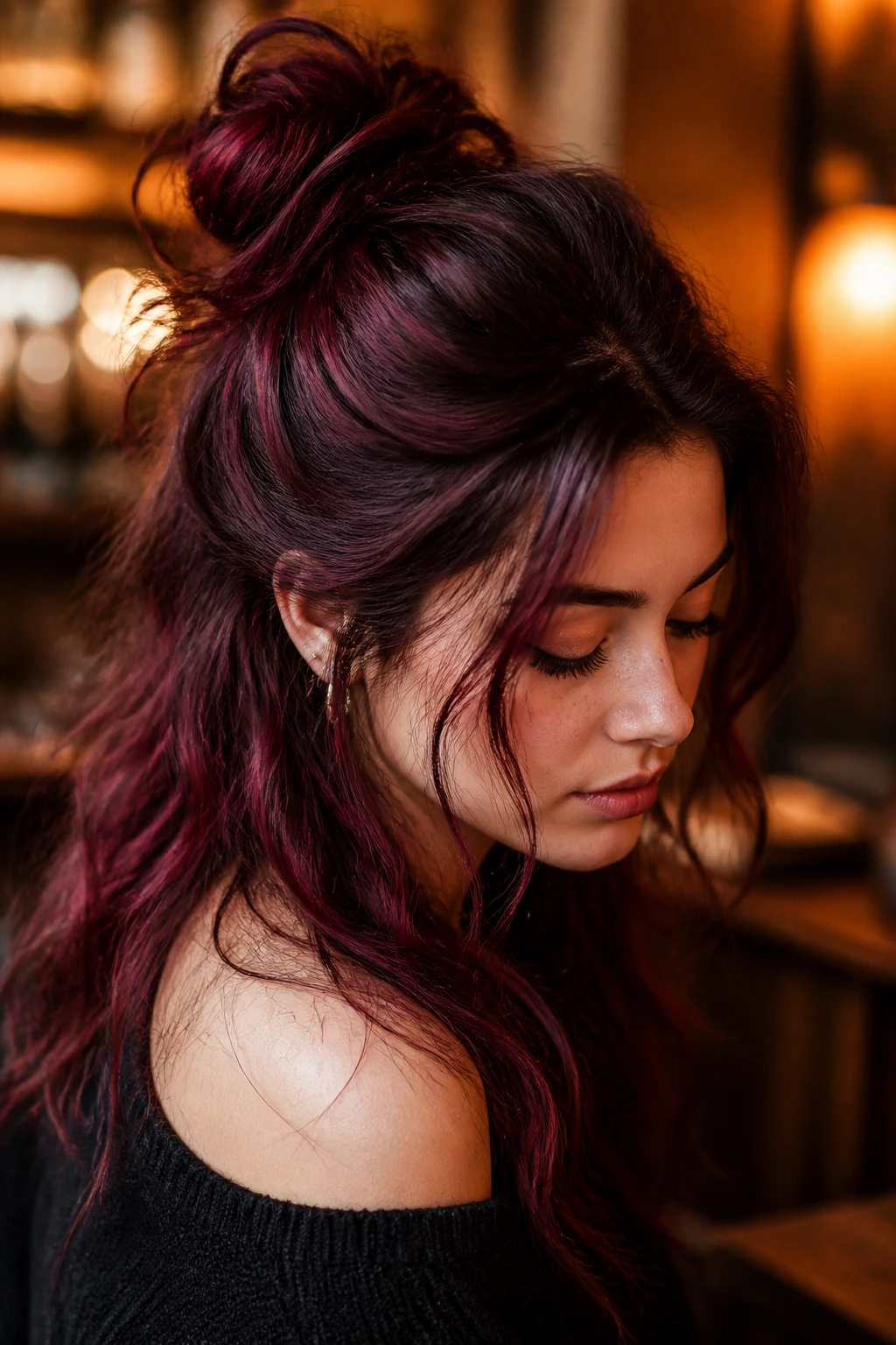 Close-up of a real woman with half-up messy bun maroon hair