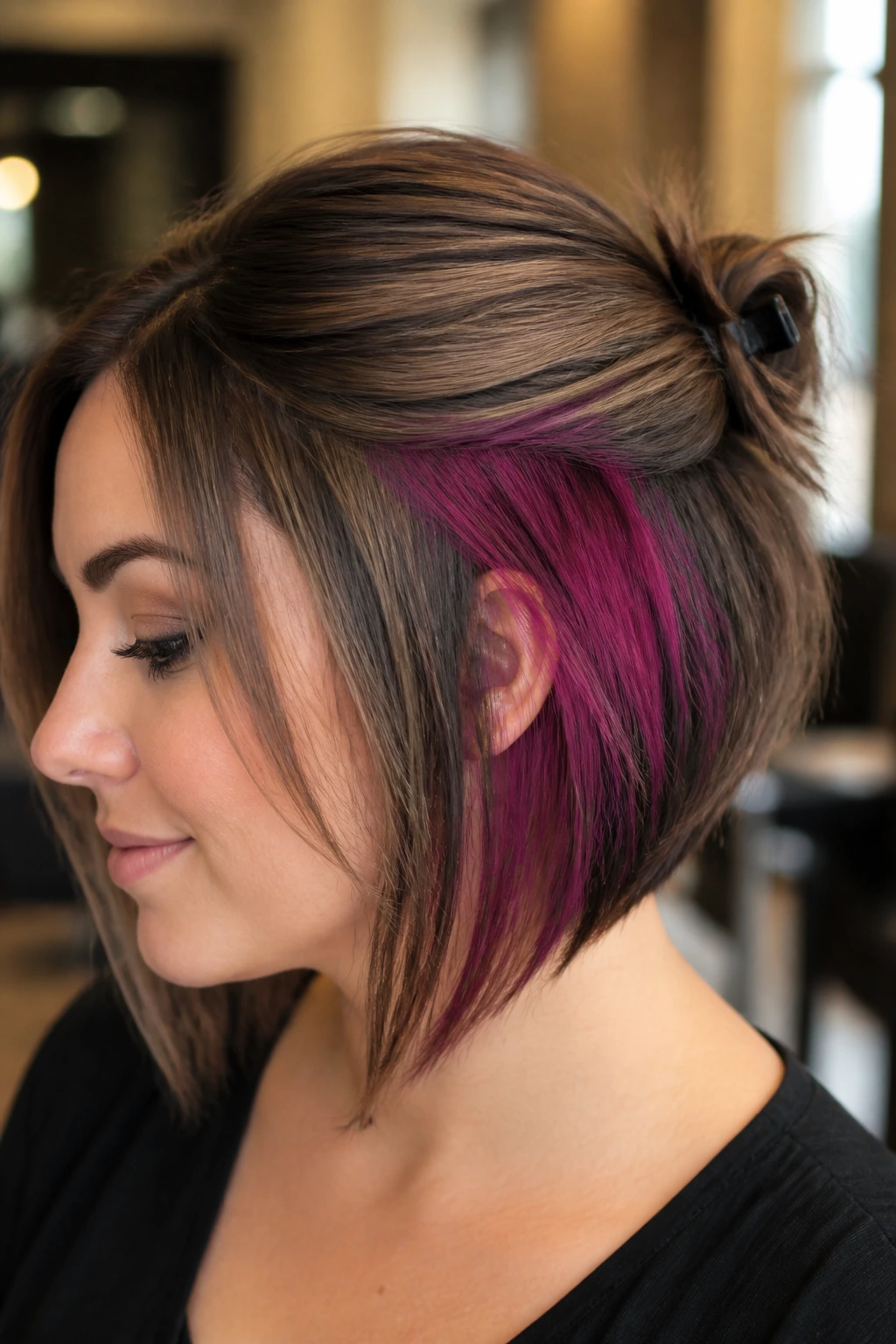 Close-up of a real woman with a hidden interior color in a stacked bob, revealed by half-up styling.