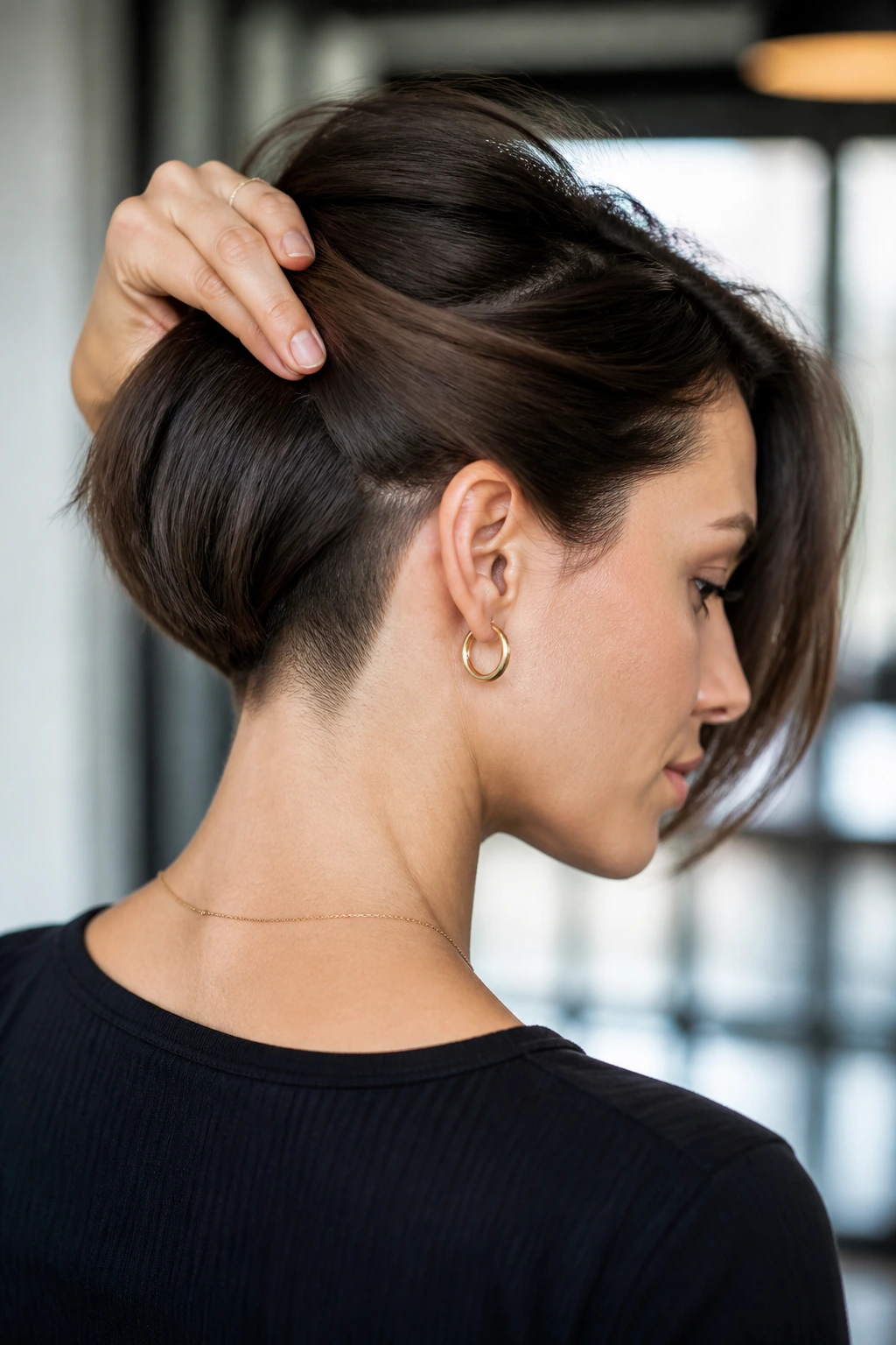 Close-up of a woman with an undercut at the nape visible as hair lifts