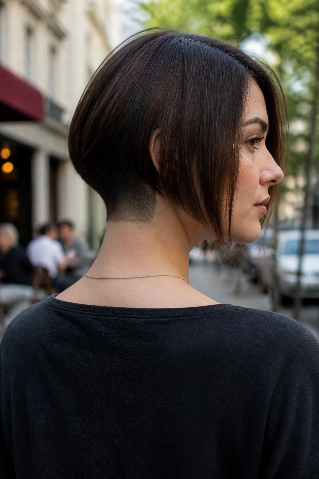 Portrait of a real woman with a long bob and tapered nape shave in an outdoor cafe setting.