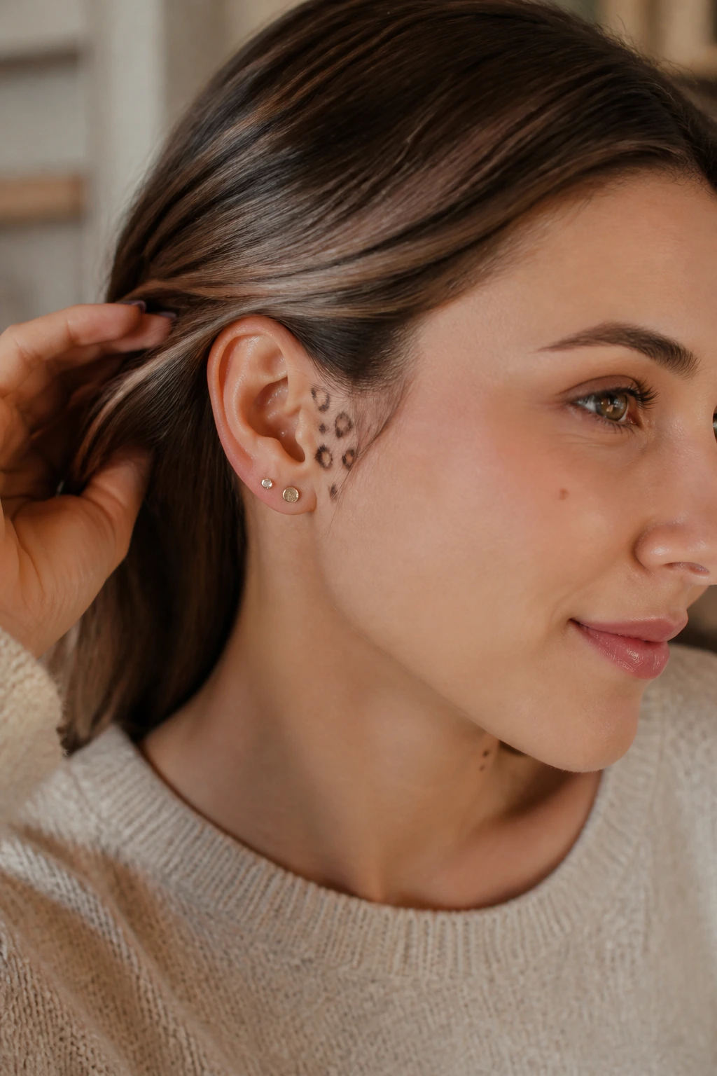 Close-up of a real person with three small leopard spots behind the ear