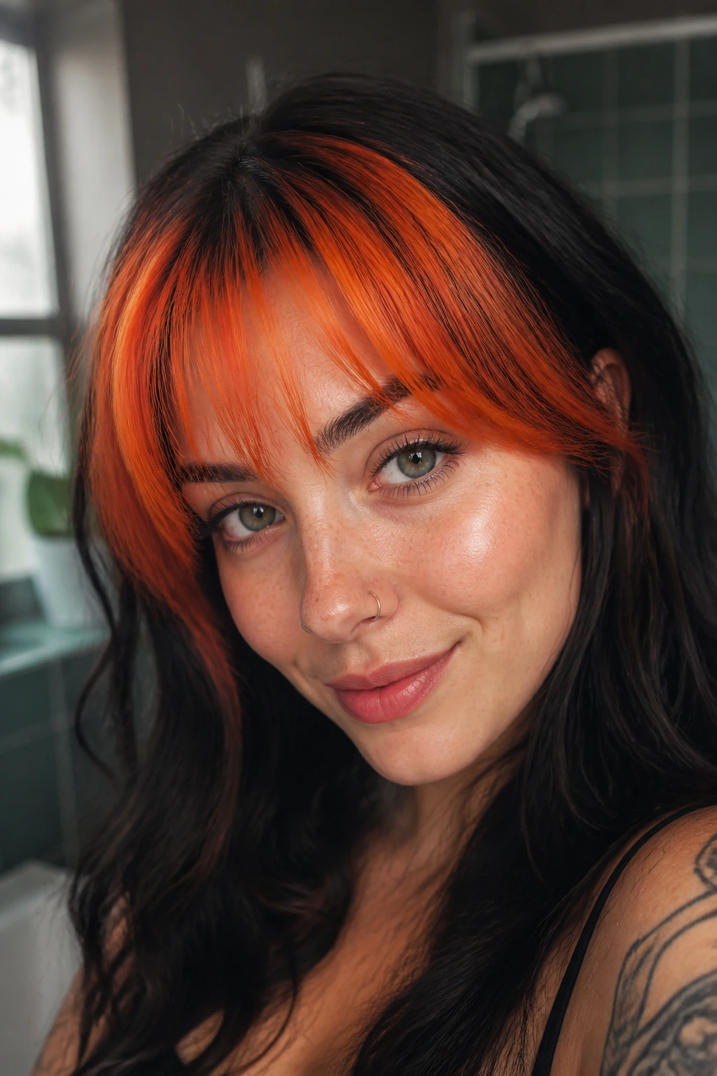 Close-up of vivid orange bangs on a real person with soft bathroom lighting