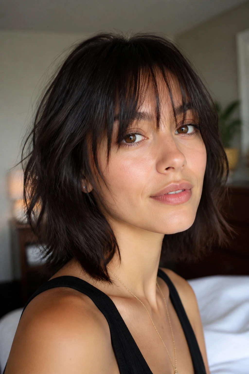 Close-up of a real woman with Piecey Brow-Skimming Shattered Bangs, vertical feathered fringe at the eyebrow.