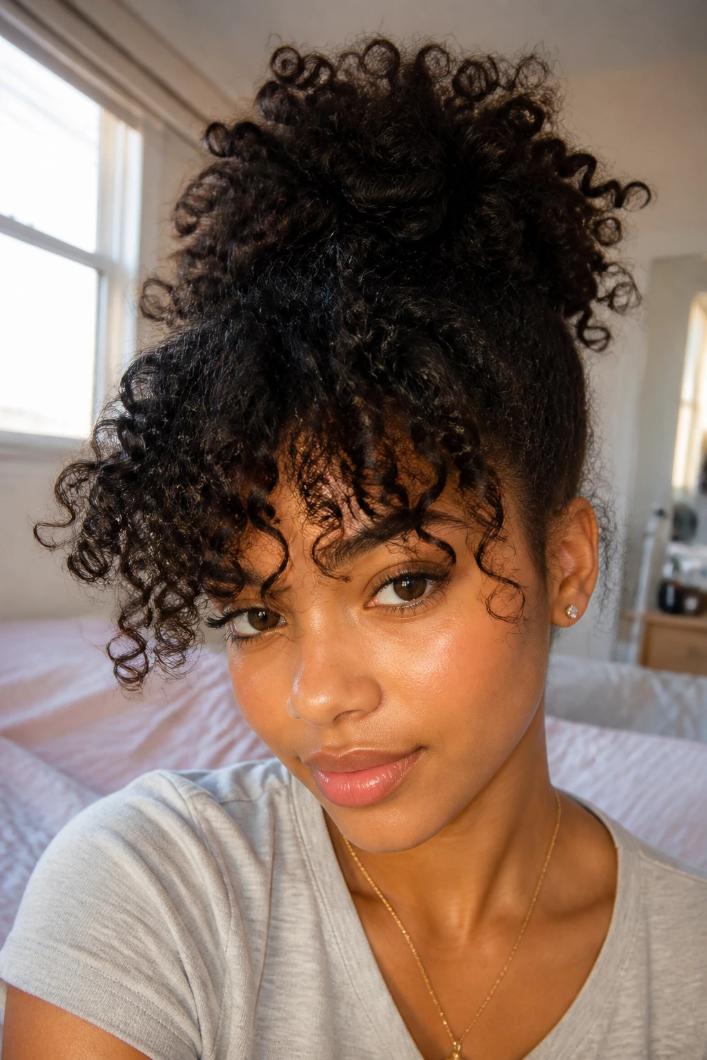 Close-up of a real person with a pineapple updo and curls cascading over the forehead