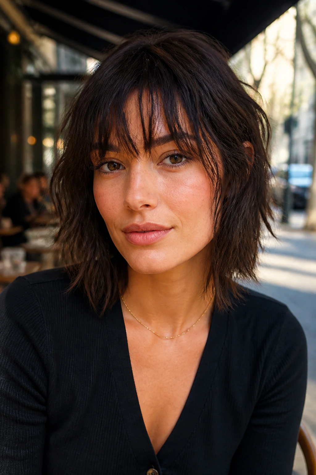 Portrait of a woman with razored shag fringe in a sunlit cafe setting
