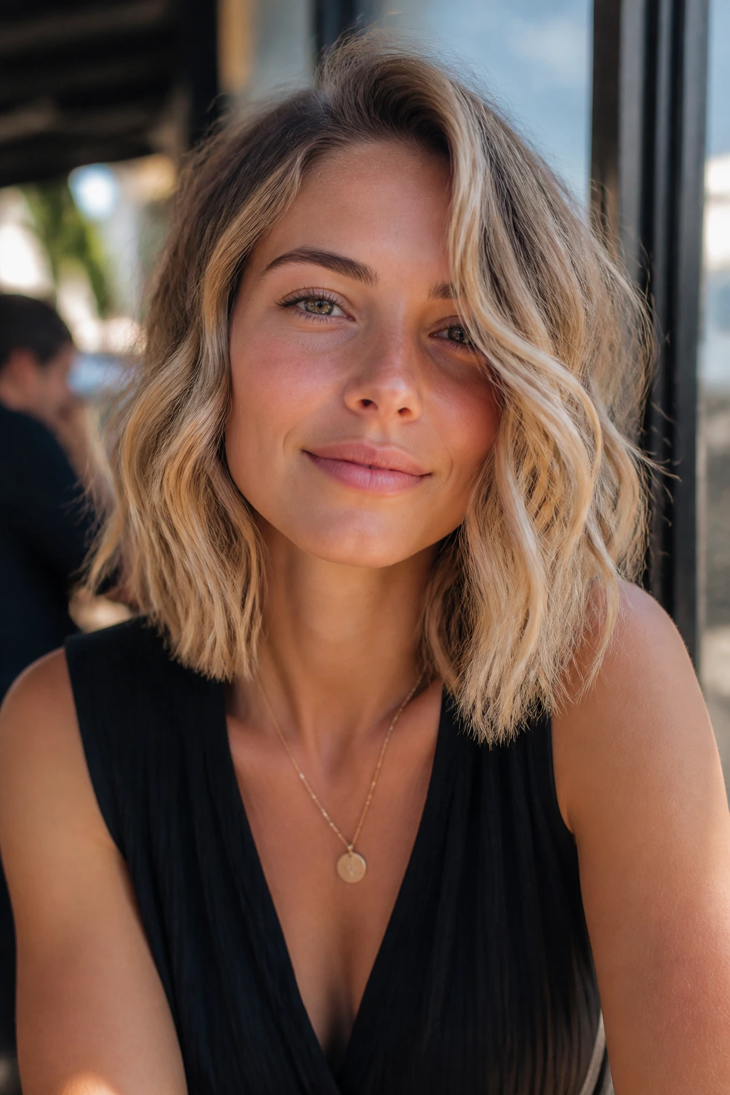 Portrait of a woman with wavy sandy blonde long bob in outdoor sunlit setting