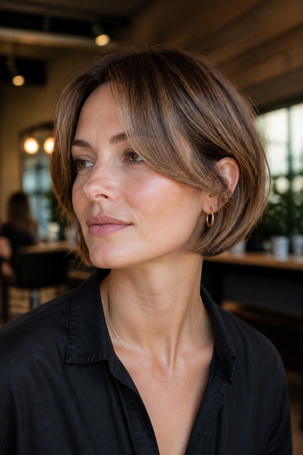 Close-up portrait of a real woman with a short bob and wide curtain bangs in warm salon light