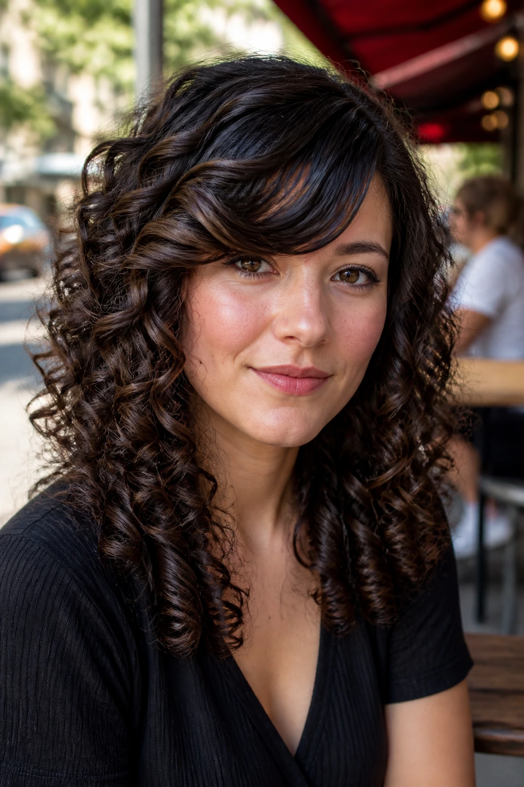 Real woman with side-swept bangs and spiral curls in an urban cafe setting