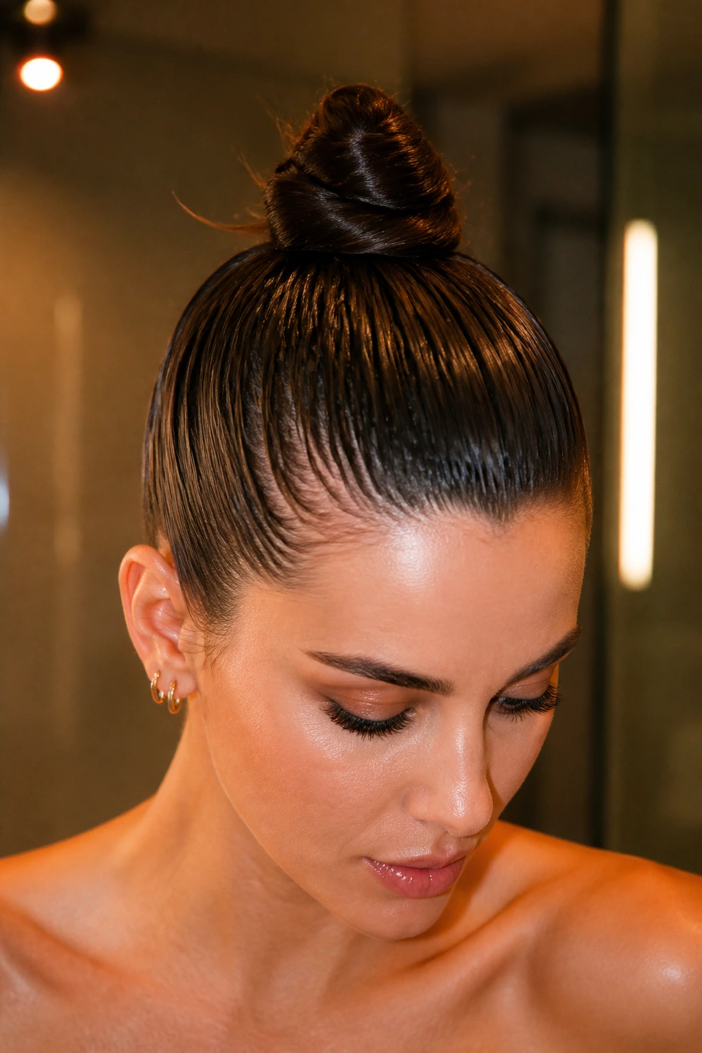 Close-up of a real woman with a high slicked-back topknot on damp hair
