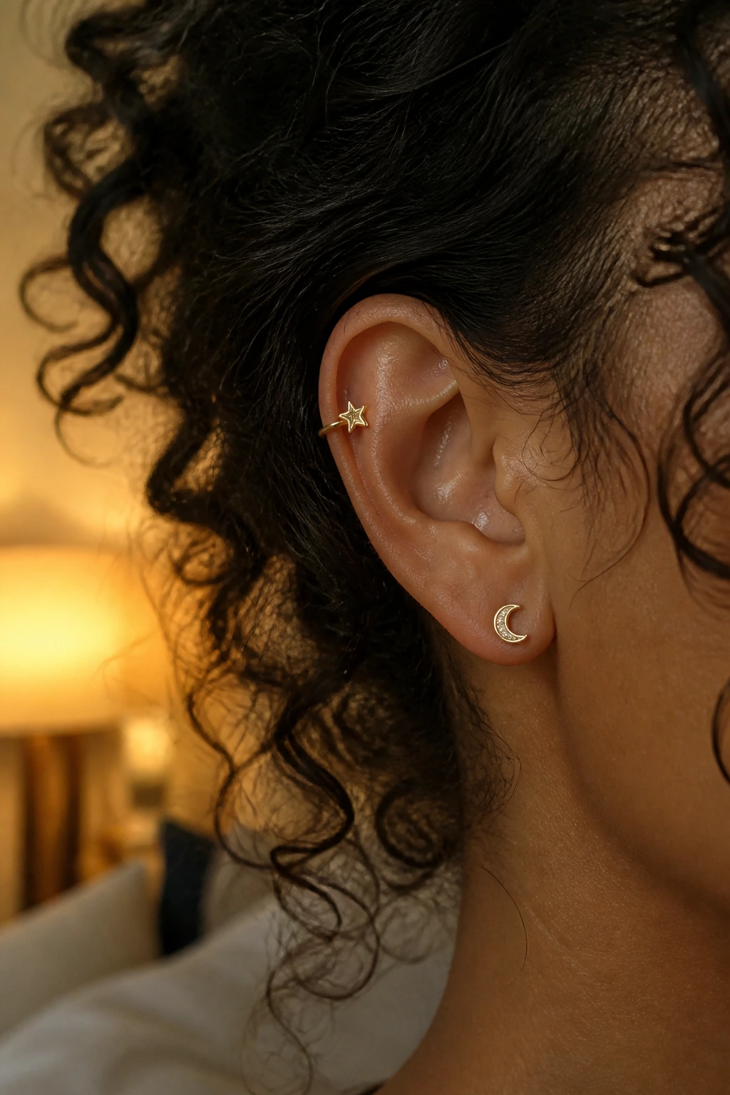 Real person wearing star and moon ear cuffs on the ear with curly hair