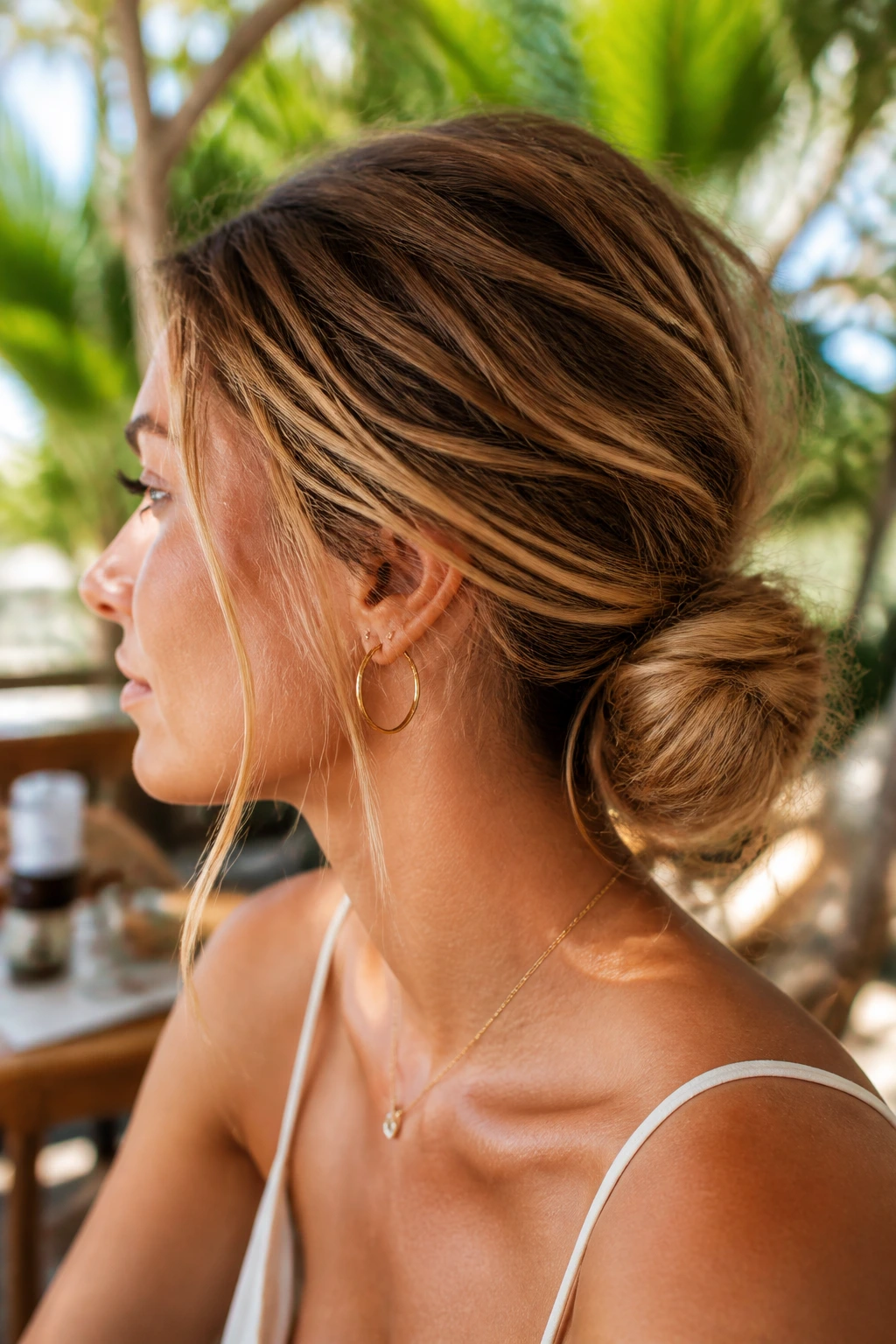 Close-up of real woman with teased low messy bun in tropical light