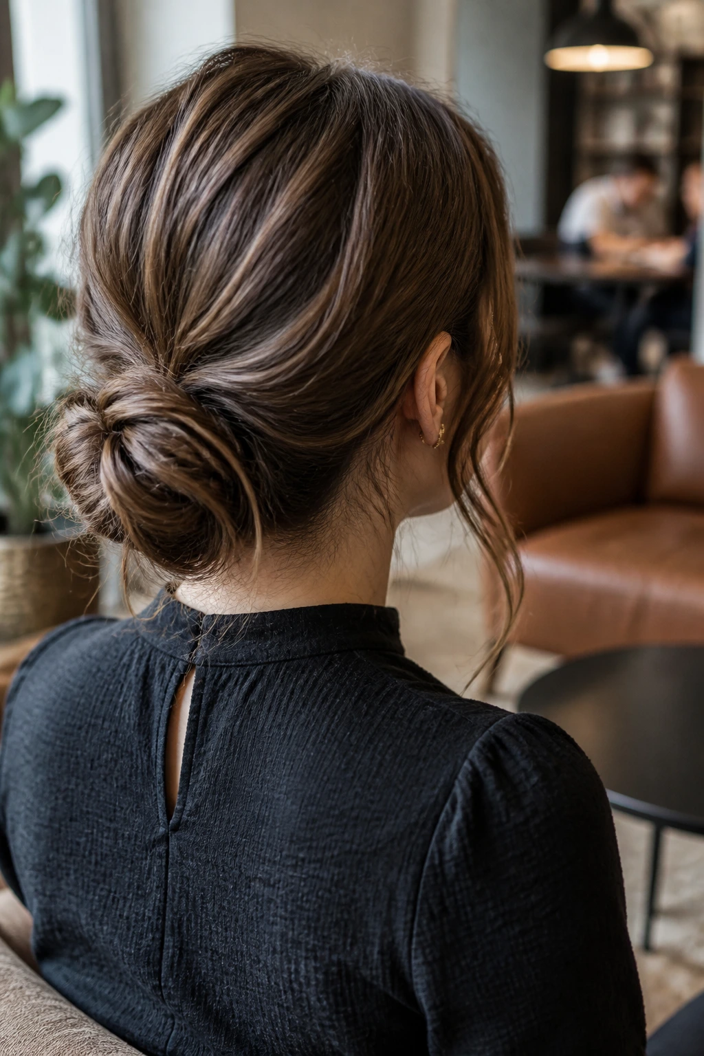 Back view of a woman with a textured low bun in a casual office setting