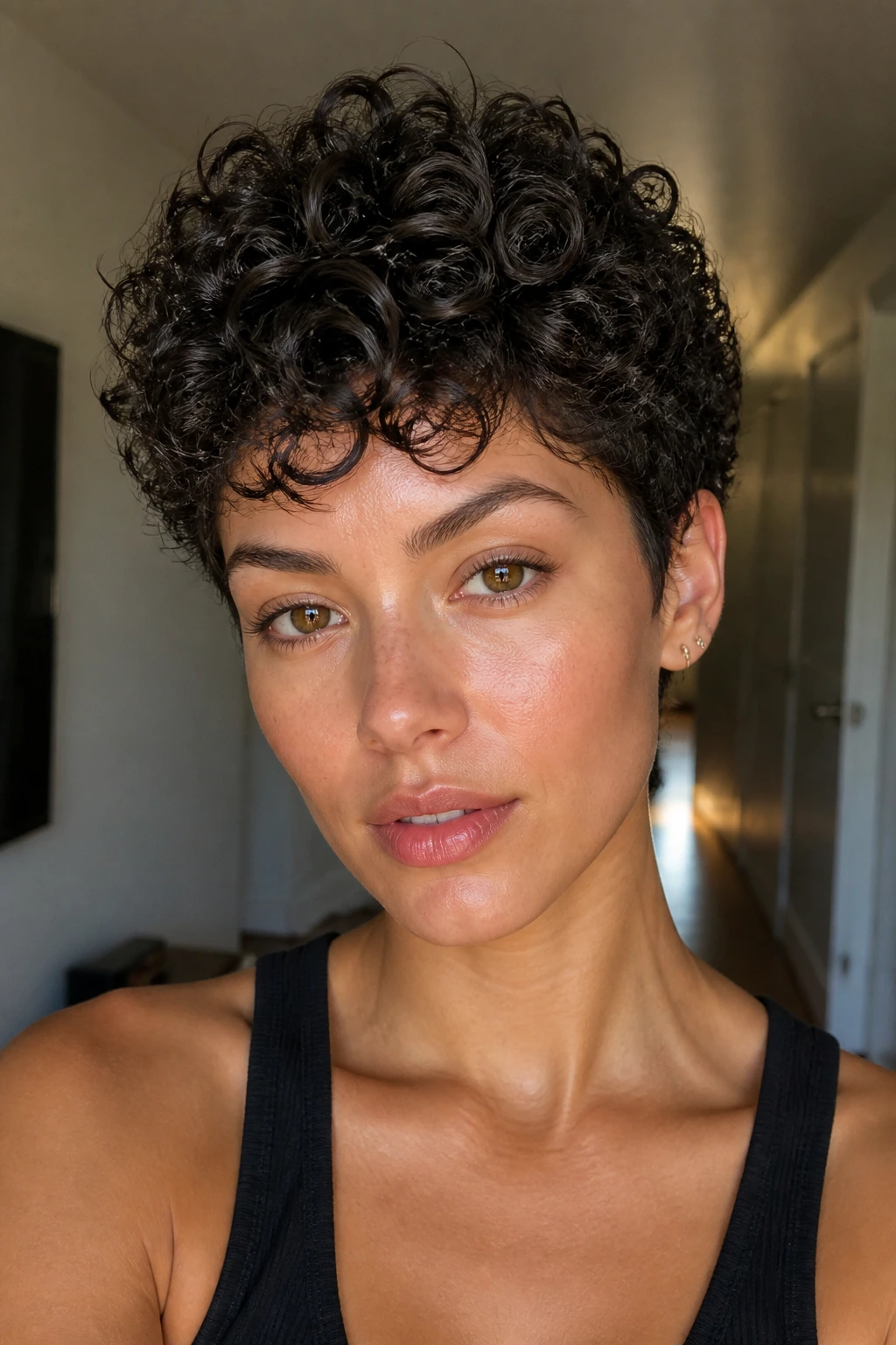 Close-up of a real person with textured curly pixie defined by pomade in warm light