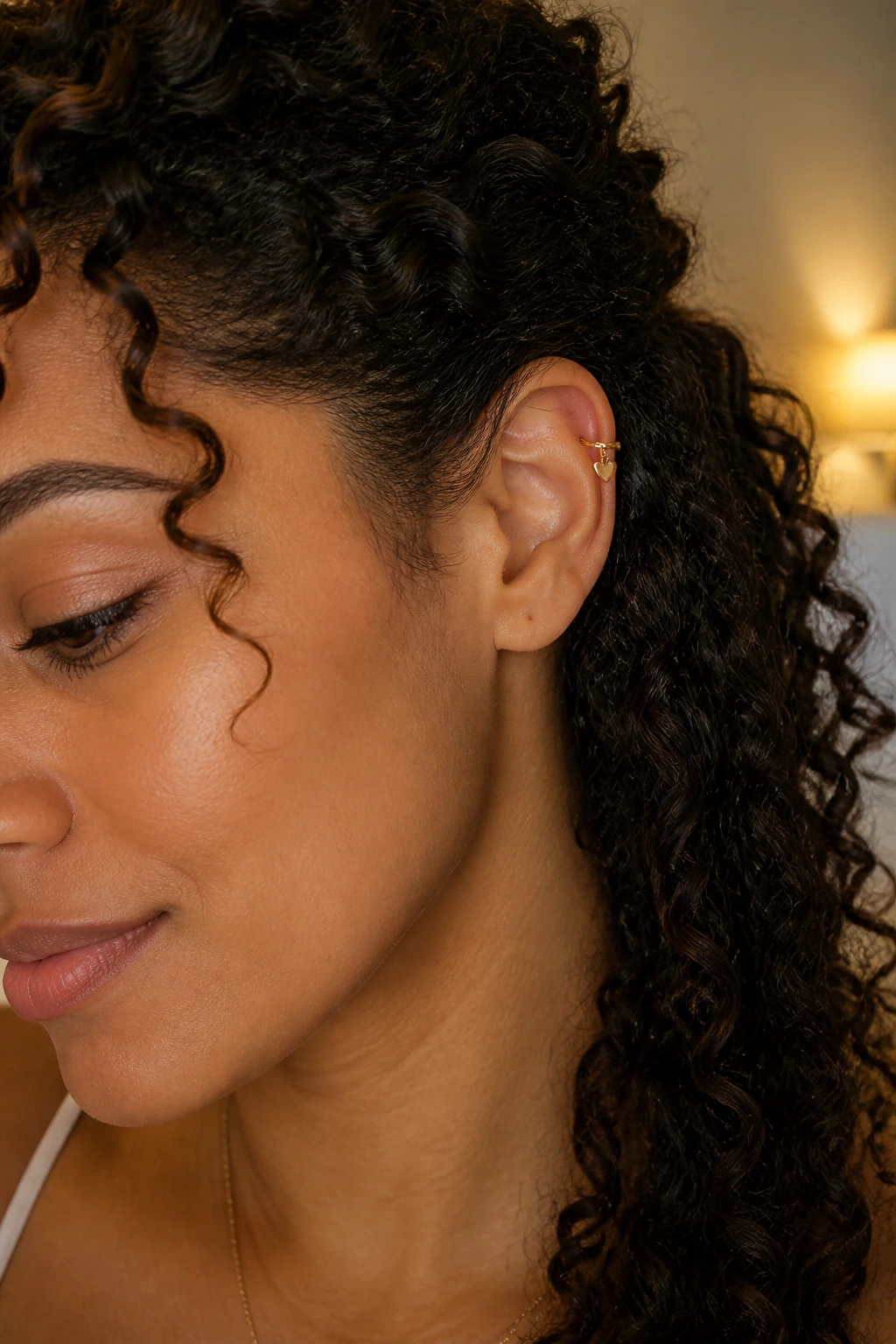 Close-up of ear with tiny heart charm cuff and side-swept curls