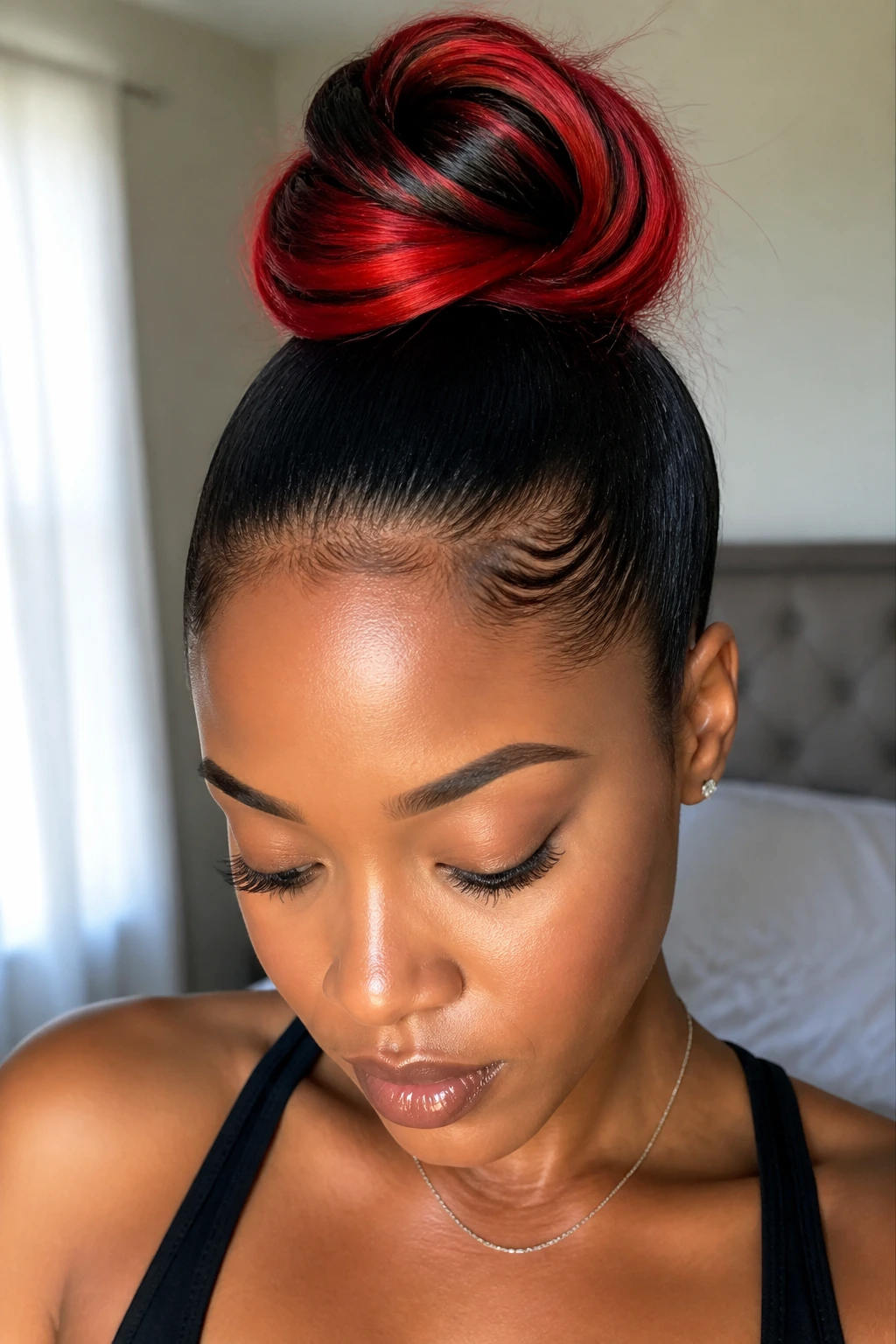 Close-up portrait of a real woman with black hair and red ends styled into a sleek top knot.