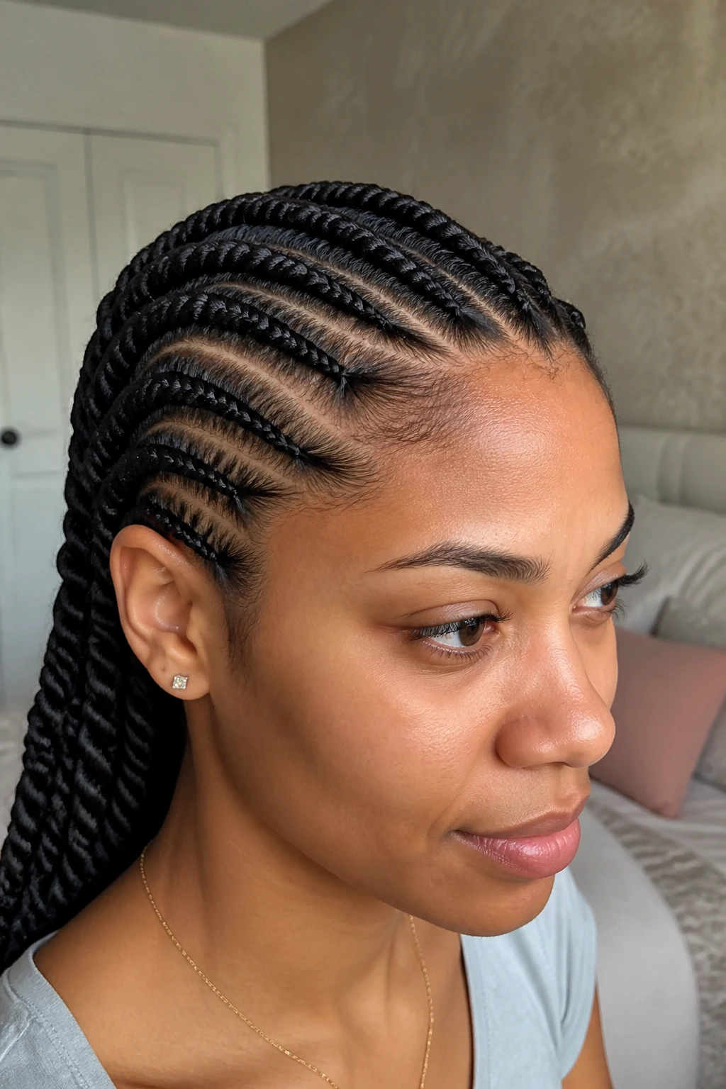 Close-up portrait of a real woman with two-strand flat twists along the scalp in a cozy bedroom.