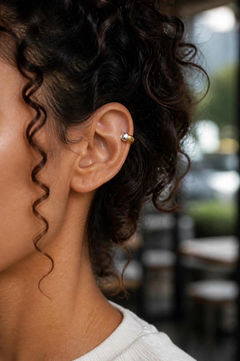 Ear with silver and gold two-tone cuff among curls