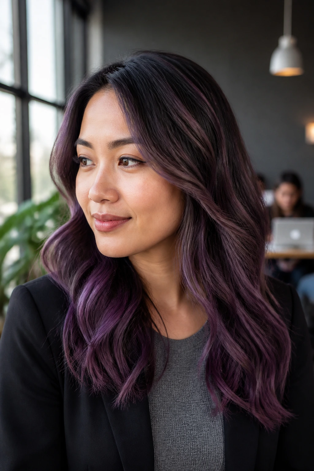 Close-up of real person with faded violet balayage on dark hair in a modern coworking space