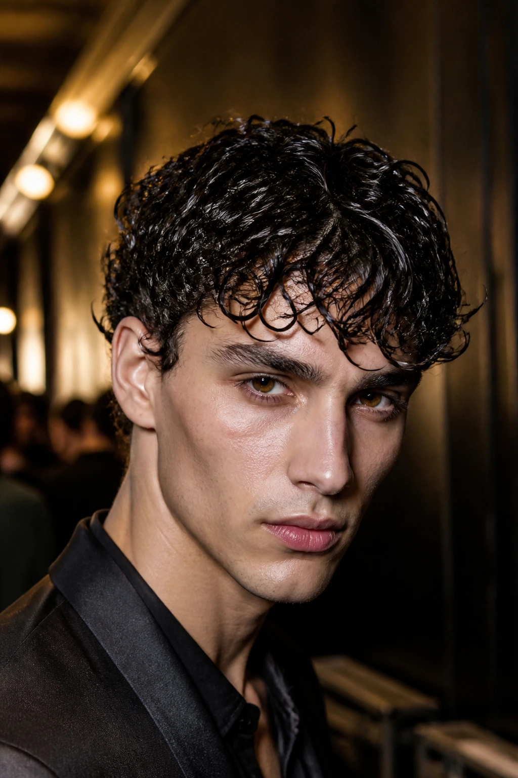Close-up of a man with wet-look curls in backstage fashion lighting