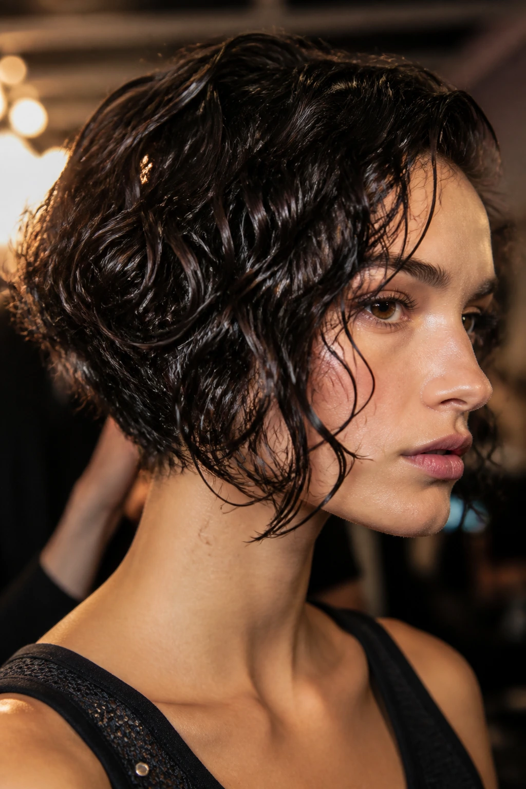 Close-up of a real woman with a wet-look inverted bob and glossy curls