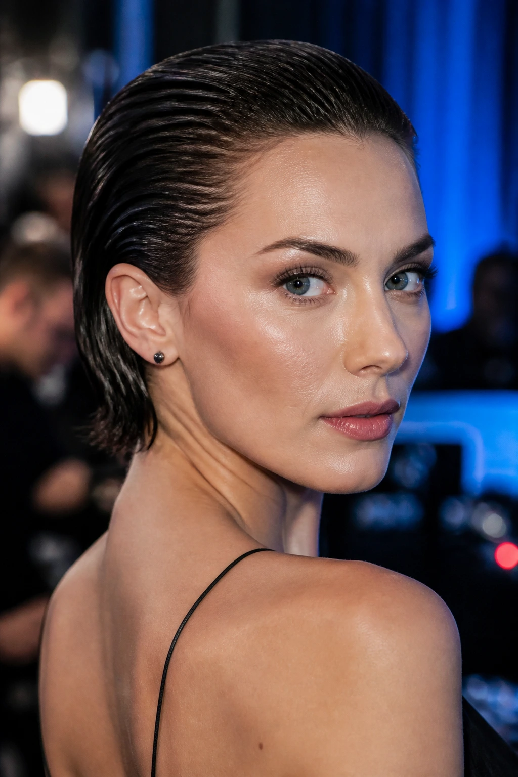 Close-up of a woman with slicked-back wet look wedge hairstyle under blue lighting
