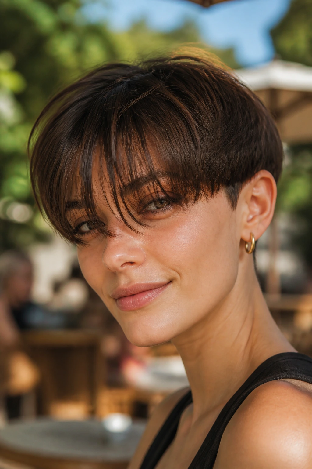Portrait of a person with a bowl-cut base and long wispy bangs in warm sunlight