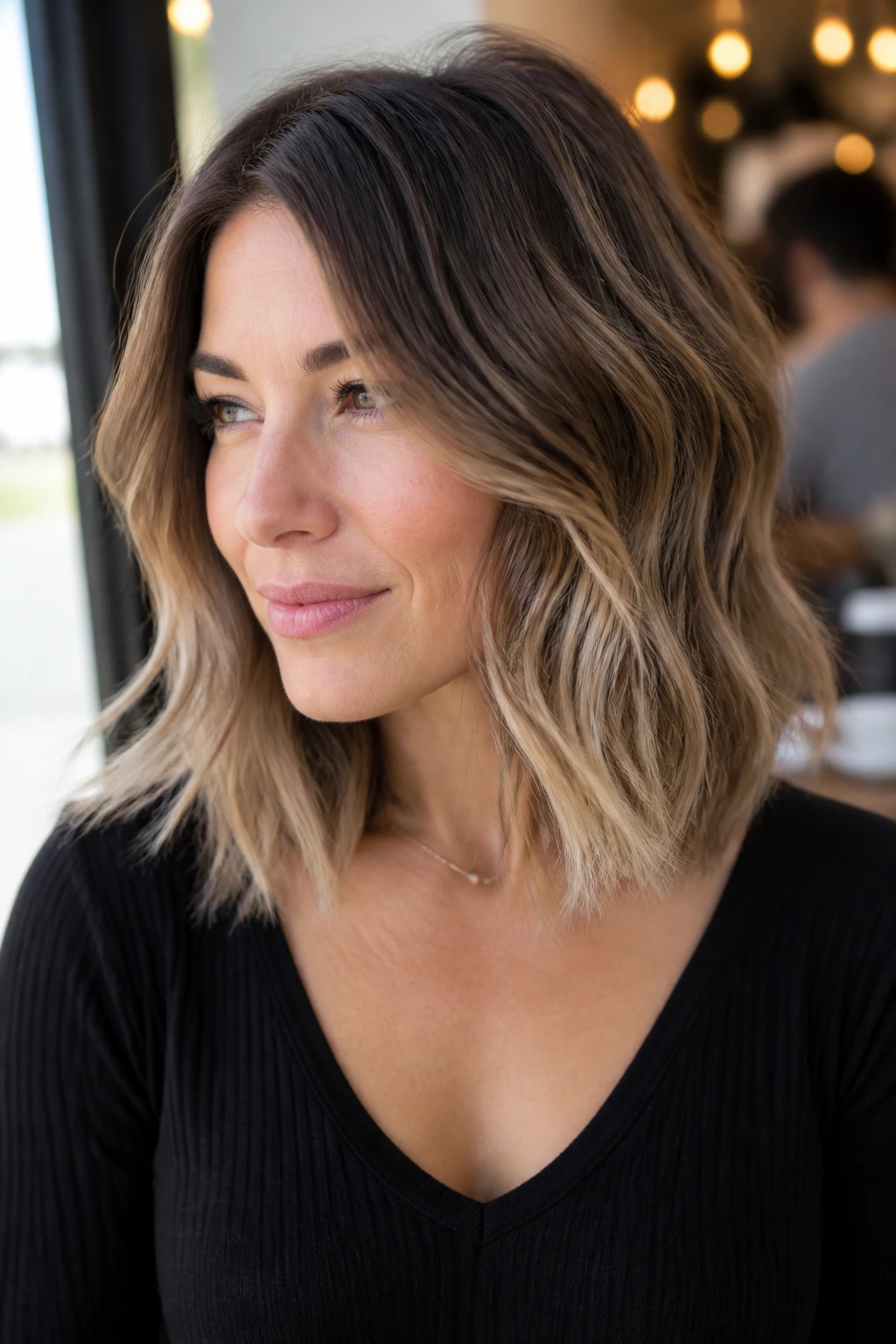 Portrait of a woman with wavy lob and balayage showing root-to-end color contrast
