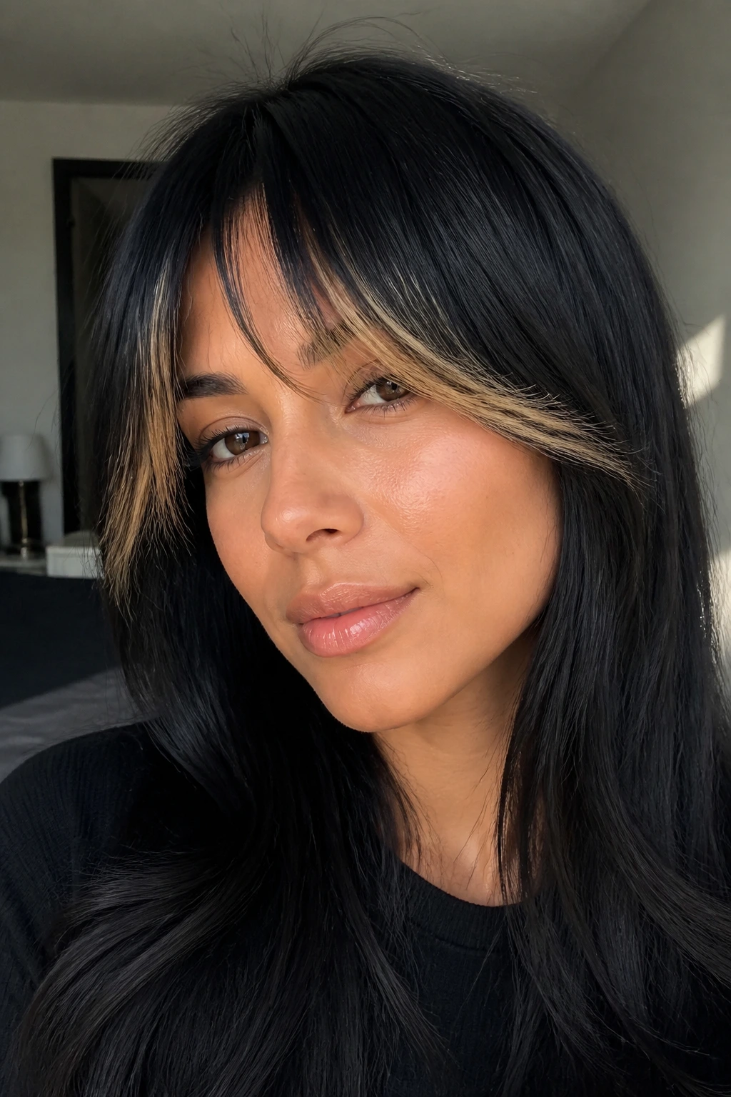 Close-up of a real person with black base hair and gold-tipped curtain bangs framing the face.