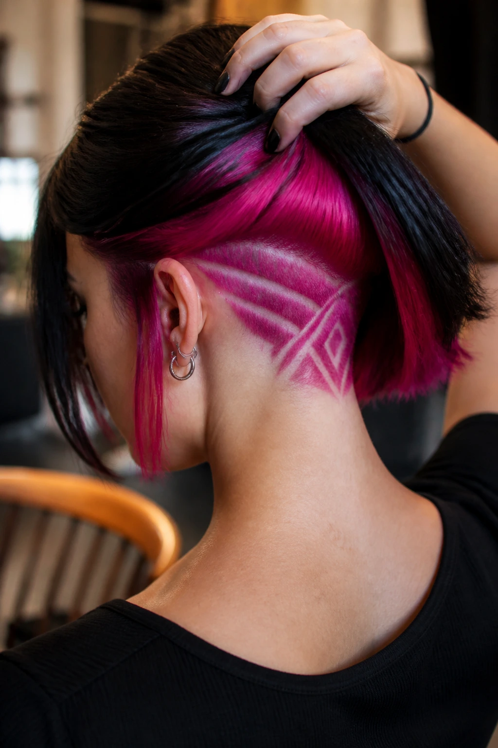Close-up of a real woman's head showing a hot-pink geometric undercut at the nape with a sharp bob.