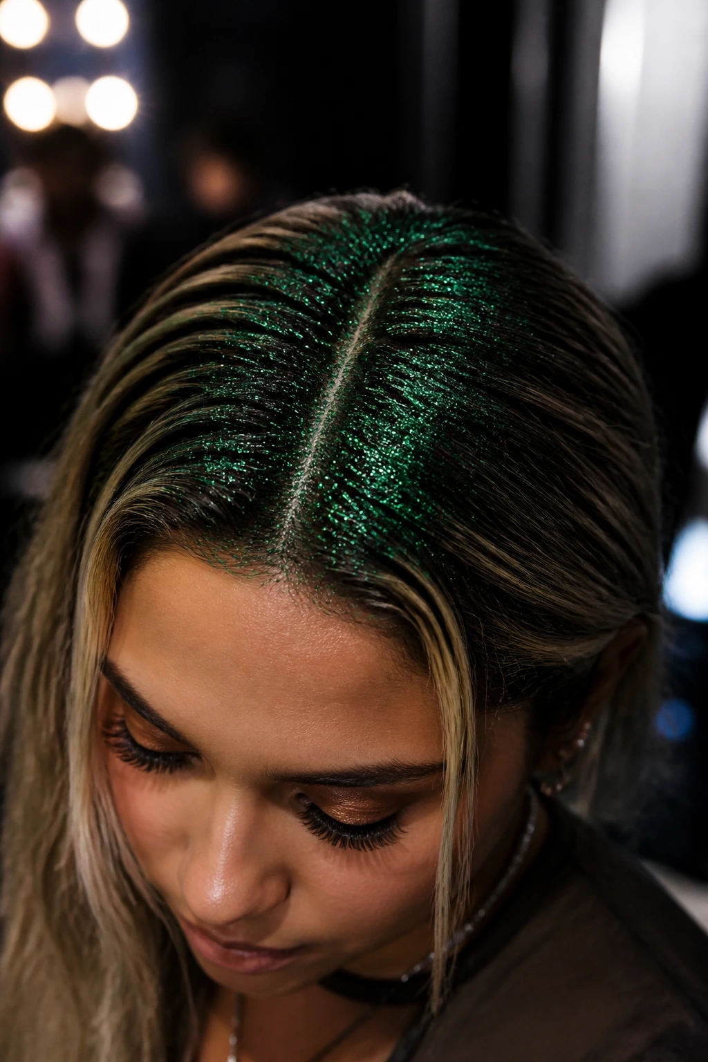 Close-up of a real person with pine needle green glitter at the roots under club lighting