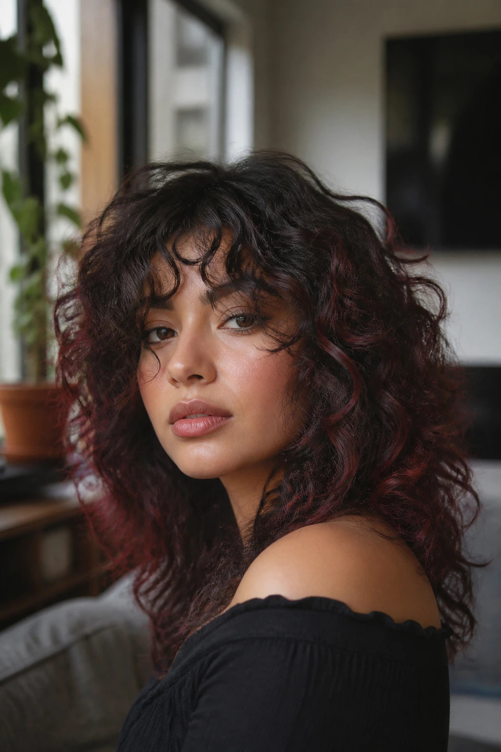Close-up of Latina woman with layered curls and dark accents in a sunlit living room
